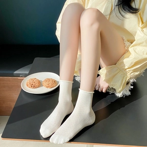 Detailed view of white cotton crew socks with hollow mesh texture and rolled cuffs
