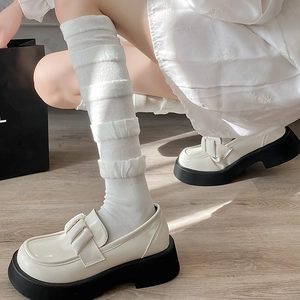 Gros plan de mocassins blancs à plateforme avec nœud et chaussettes à froufrous