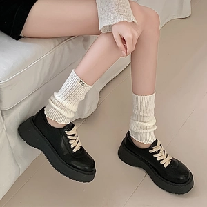Detail of white ribbed leg warmers paired with black platform leather shoes in a casual set