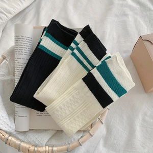 Detailed close-up of white and black ribbed knit knee-high socks with college style stripes