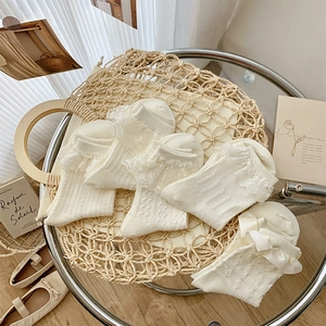 Flat lay of cream lace socks with bows and ribbon details in a minimalist setting