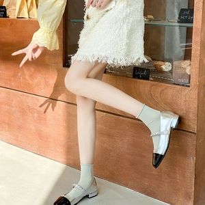 Detail of silver Mary Jane flats with black toe cap and pearl rhinestone strap