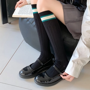 Detail of JK style black knee high socks with green and white stripes at the top band