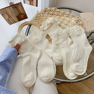 Detail of white lace trim socks featuring vertical stripes and ruffled edges on chair