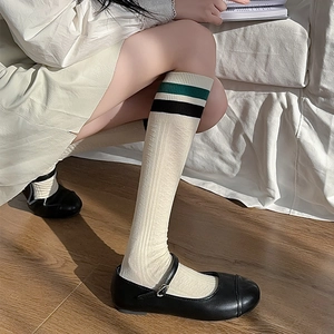 Detailed knit texture of white knee-high socks with green stripes and ribbing
