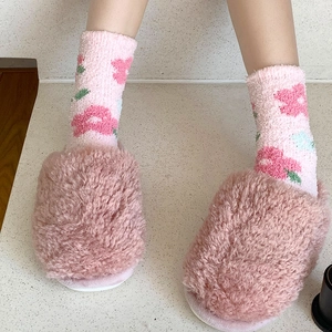 Dettaglio di calze in pile rosa con motivi floreali e pantofole di peluche coordinate