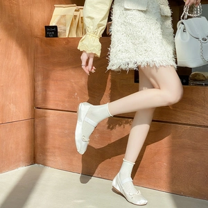 Close-up of white satin Mary Jane ballet flats with delicate bow and elastic strap details