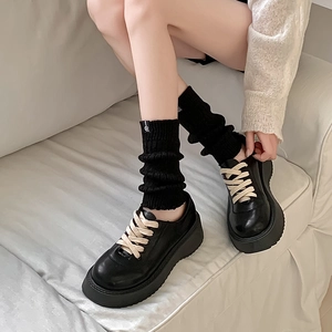 Detail of black platform loafers with beige laces and knitted leg warmer socks