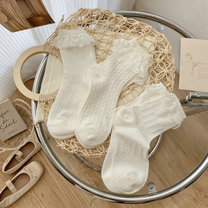 Three pairs of cream white lace-trim ankle socks displayed on a woven tray for Lolita style