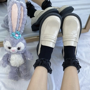 Cream white patent leather platform loafers with black soles shown in top-down view