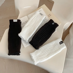 Knit leg warmers in black and white with vertical stripes and minimalist cloth labels