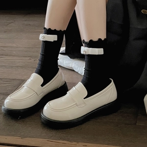Chic beige platform loafers paired with black ballet bow socks on dark wood flooring
