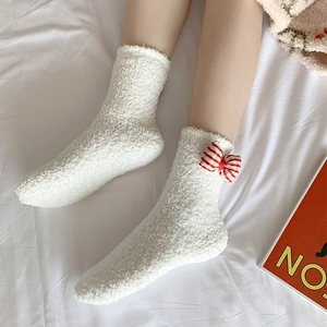 Close-up of fluffy white coral fleece socks with a cute red and white striped bow