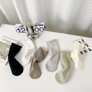 Flat lay of six pairs of solid color cotton crew socks with rolled cuffs in multiple hues