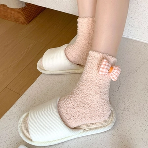 Detailed texture of thick coral fleece socks with orange plaid bow decoration