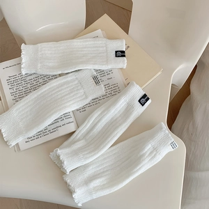 Close-up of white knitted leg warmers with ribbed texture and chic fabric labels