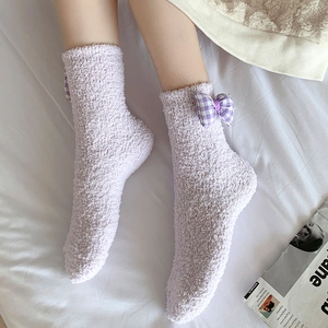 Close-up of plush purple coral fleece socks with checkered bow and soft texture
