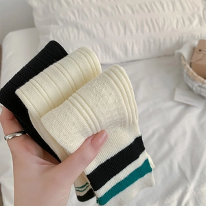 Detail of ribbed knit cotton knee-high socks with vintage stripe accents in neutral tones