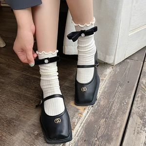 Ballet style white mid-calf socks with ruffles and black bow paired with Mary Jane shoes