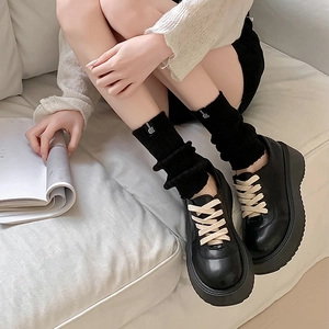 Close-up of black platform shoes with beige laces and stylish knitted leg warmer detail