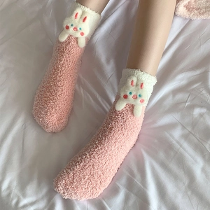 Close-up of thick coral fleece winter socks with a 3D cute rabbit doll on the cuff