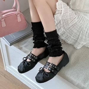 Détail de jambières en tricot noir avec nœuds et chaussures ballerines Mary Jane