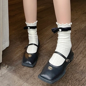 Detail of white ruffle socks with black bow and rhinestone paired with Mary Jane shoes