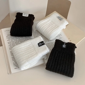 Close-up of ribbed knit leg warmers in black and white with minimalist cloth labels