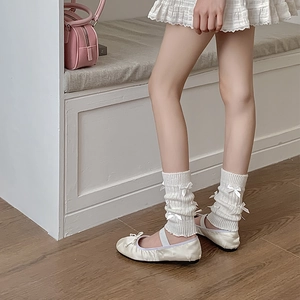Gros plan de jambières en tricot blanc avec rubans et ballerines sur sol en bois