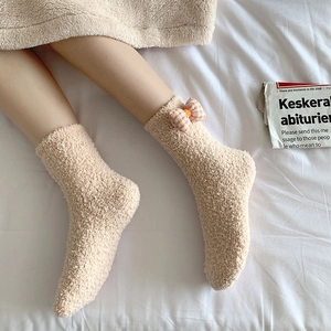 Close-up of fluffy coral fleece socks in beige featuring a plaid bow decoration