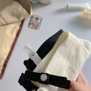 Detailed close-up of ribbed knit socks featuring velvet bows and rhinestone flower charms