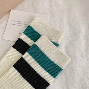 Detail of white and green striped knitted knee-high socks with vintage academic style texture