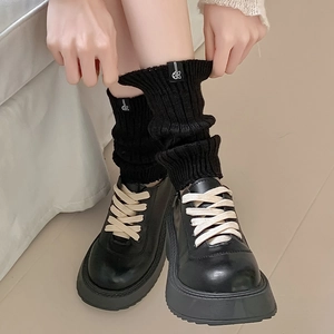 Detail of black platform loafers with white laces and knit leg warmers in retro style