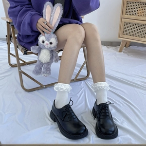 Close-up of matte black oxford shoes with white lace ruffle socks in JK school style