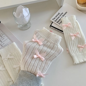 Détail de mitaines en tricot blanc crème avec de jolis nœuds en ruban rose