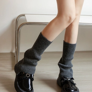 Close-up of dark grey knitted leg warmers with ribbed texture and heart-buckle loafers