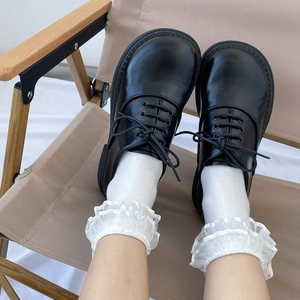 Detail of white lace ruffle socks paired with black matte leather oxford shoes in JK style
