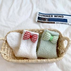 Close-up of coral fleece warm socks with checkered bows in a woven basket