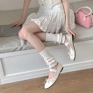 Détail de jambières en tricot crème avec nœuds roses dans un style balletcore doux