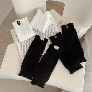 Detail of knitted leg warmers in black and white with ribbed edges and woven label