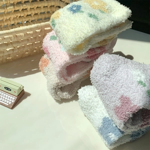 Dettaglio ravvicinato di calze spesse in pile corallo con motivi floreali pastello