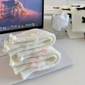 Détail de jambières en tricot blanc avec de délicats nœuds en ruban doux