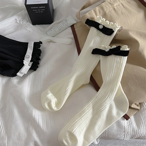 Close-up of ballet style socks with ruffled edges and black velvet bows with rhinestones