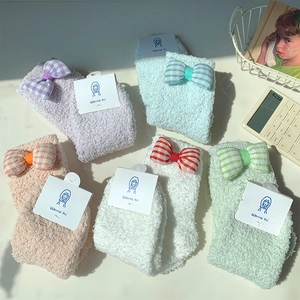 Close-up of five pairs colorful coral fleece socks with plaid bows and soft texture