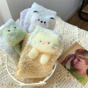 Detailed view of three pairs of soft coral fleece animal socks in a white wire basket