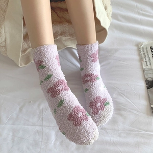 Dettaglio di calzini in pile corallo con motivi floreali rosa e una consistenza morbida
