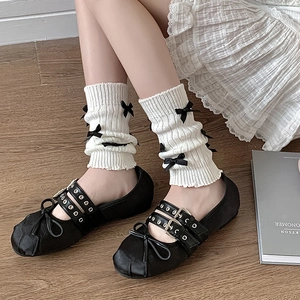 Détail de jambières blanches côtelées avec nœuds noirs et chaussures Mary Jane