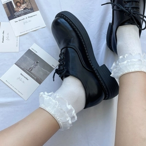 Detail of white cotton socks with lace trim paired with black platform oxford shoes