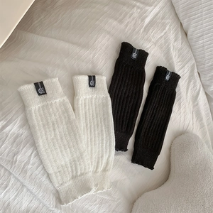 Detailed knit texture of black and white leg warmers with ribbon butterfly woven labels