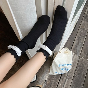 Detail view of black knit crew socks with white bows and sparkling rhinestones